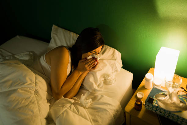 istock Sick woman with a runny nose in bed 1346786212