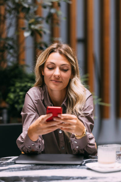 istock Happy Businesswoman Using Mobile Phone in a Cafe 1346787119