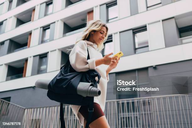Happy Sporty Woman In A White Sweatshirt Using A Mobile Phone Outdoors Stock Photo - Download Image Now