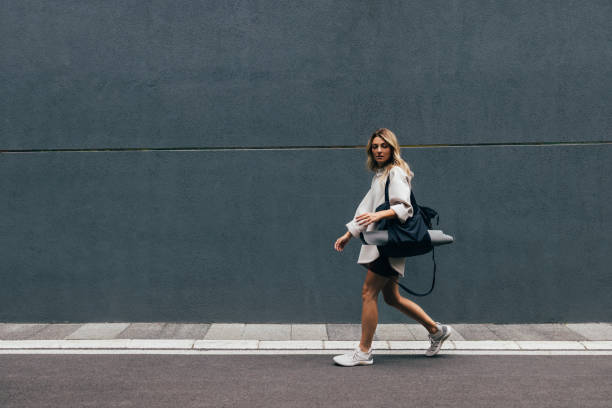 도시에서 걷는 흰색 스웨트 셔츠를 입은 스포티 한 여성 - gym bag 뉴스 사진 이미지