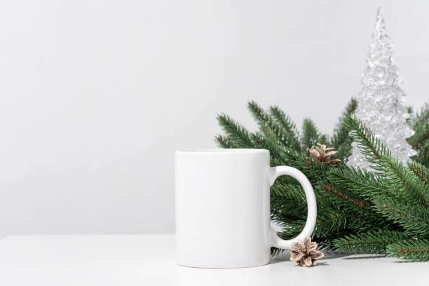 istock Christmas mockup one white empty tea mug on a white table and branches of a Christmas tree wreath. 1346789386