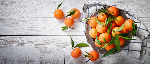 Tangerines with leaf on rustic wooden background, copy space, flat lay.