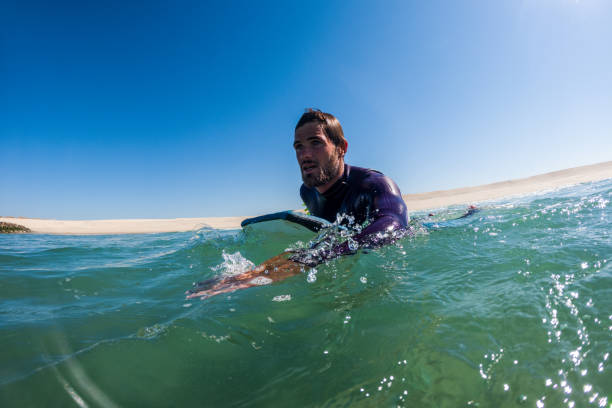 istock Bodyboarder rowing over the water 1346792320