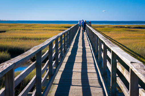 Late season visitors enjoy warm October temperatures as they walk along the quarter mile long Bass Hole boardwalk in Yarmouth, Massachusetts.