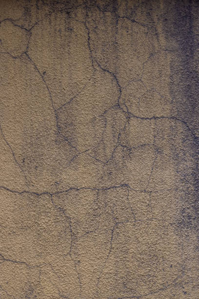 istock cracked dusty yellow rough plaster wall with gray smudges 1346794570