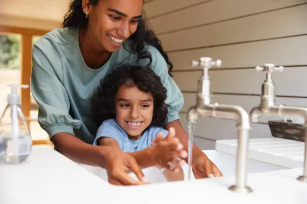 Photo of Mother helping young son wash hands in sink