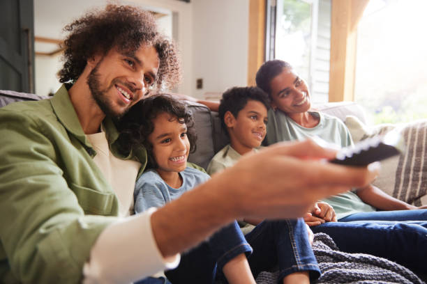 istock Family watching TV with father using remote 1346794902