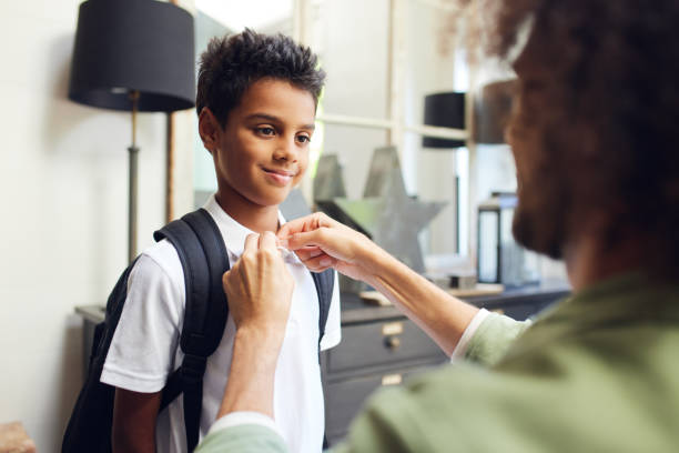 istock Boy smiling as father buttons his shirt 1346794924