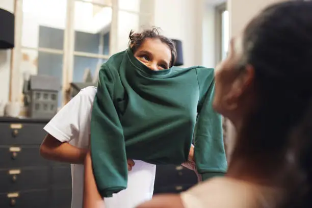 Boy with school jumper stuck on his head