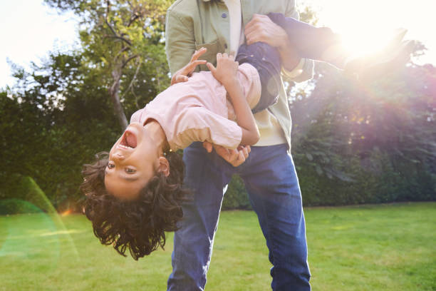 istock Boy being held upsidedown in garden with mouth open 1346794946
