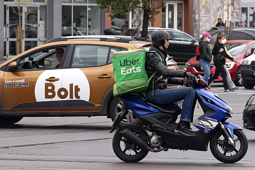 Bucharest, Romania - October 06, 2021: An Uber Eats food delivery courier on a scooter.
