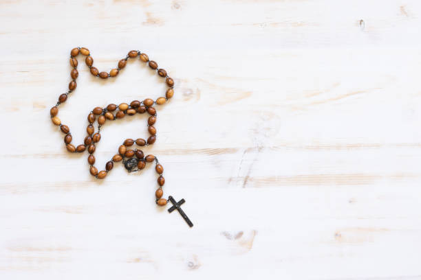 Rosary with wood beads and a dark metal crucifix on a white wood background with copy space