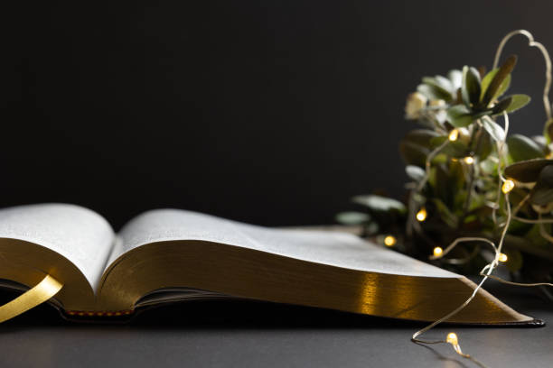 istock Open bible with Christmas decor border into black 1346799599