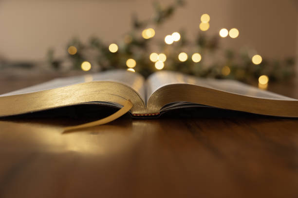 Open bible on dark wood with golden lights stock photo