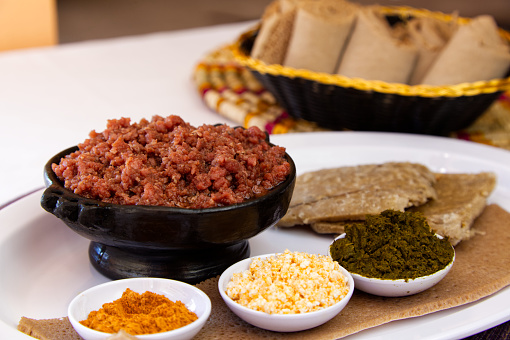 Traditional Ethiopian kitfo (marinated minced raw beef) served with spices and injera bread.