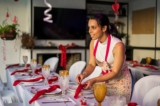 30-year-old Latin woman dressed casually wearing an apron is decorating the tables of a party