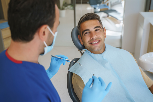 Paciente joven que se somete a tratamiento dental en el consultorio del dentista photo