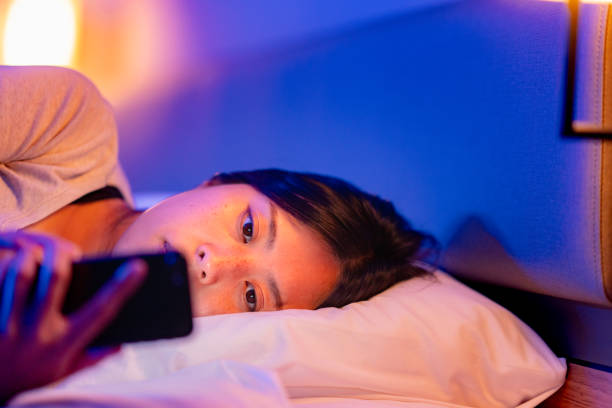 istock Young woman using smart phone in bed at night at home 1346840484