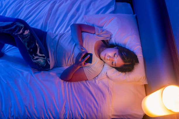 istock Young woman using smart phone in bed at night at home 1346841278