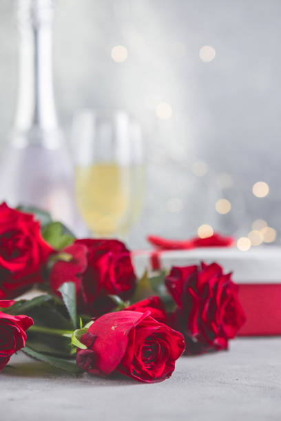 istock Champagne and red roses with bokeh. Valentine's setting with red roses and present 1346847381