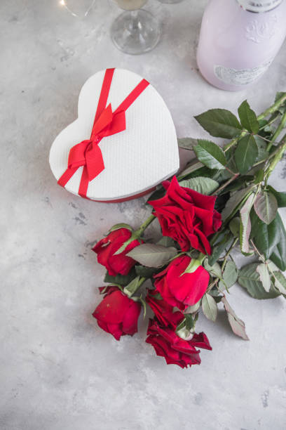 istock Flat lay composition with beautiful red roses and bottle of champagne on light background, space for text. Valentine's Day celebration 1346847391