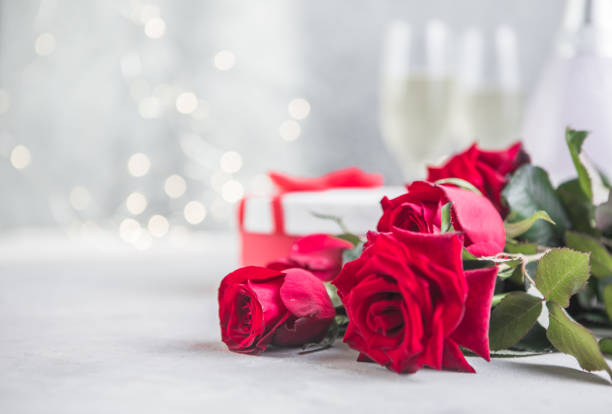 istock Champagne and red roses with bokeh. Valentine's setting with red roses and present 1346848162
