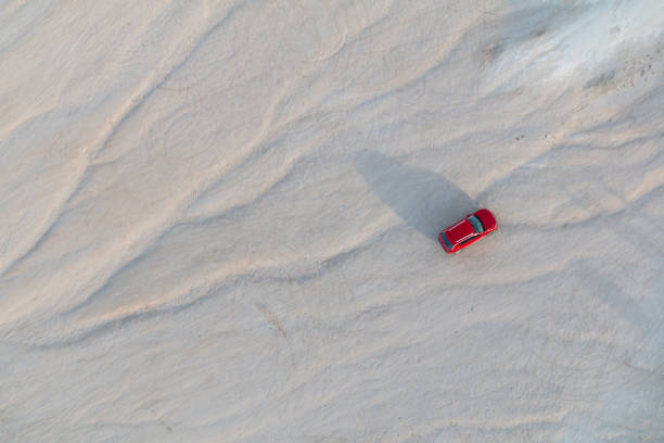 istock Red car parked on white dune background 1346849391