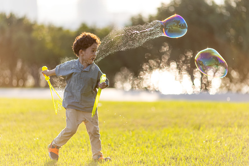 A little boy playing with soap bubbles in the park