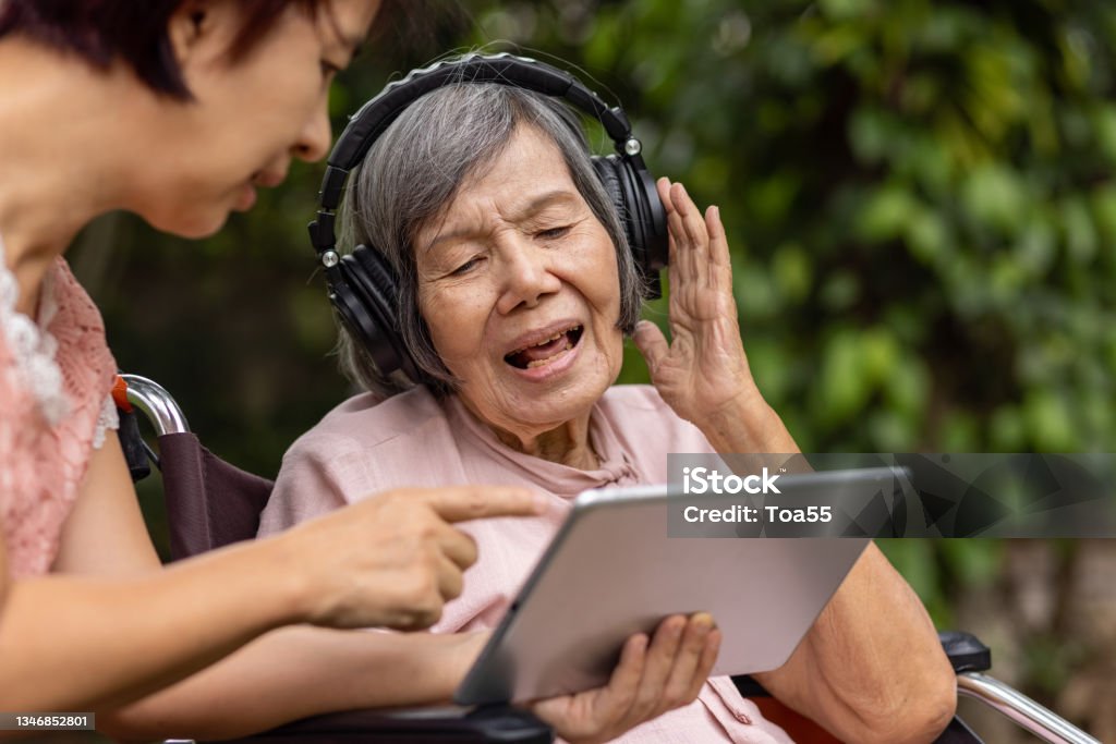senior woman and daughter listening music with headphone in backyard Senior Adult Stock Photo