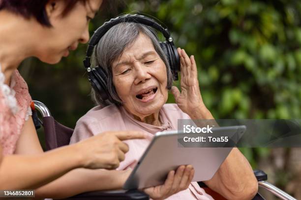 Senior Woman And Daughter Listening Music With Headphone In Backyard Stock Photo - Download Image Now