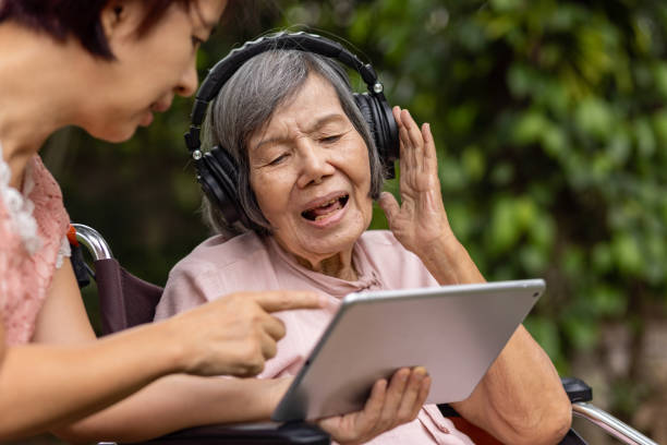 senior woman and daughter listening music with headphone in backyard - computer two people asian ethnicity women imagens e fotografias de stock