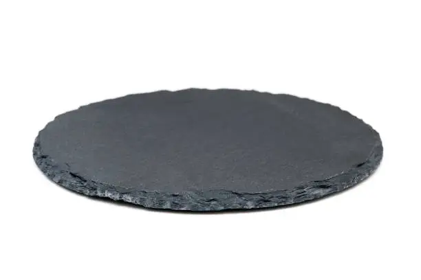 Photo of Natural black stone slate as a tray. Side view of slate board isolated on white