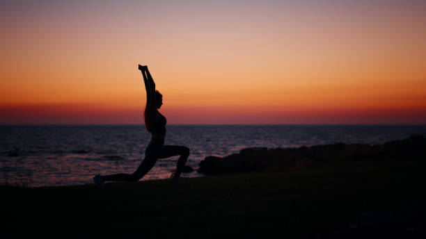 istock Active woman stretching body during sunset over ocean 1346857424