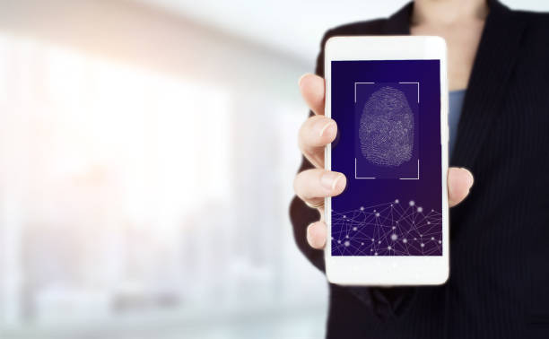 istock Password control through fingerprints. Hand hold white smartphone with digital hologram fingerprint sign on light blurred background. Biometric and security concept. 1346862025