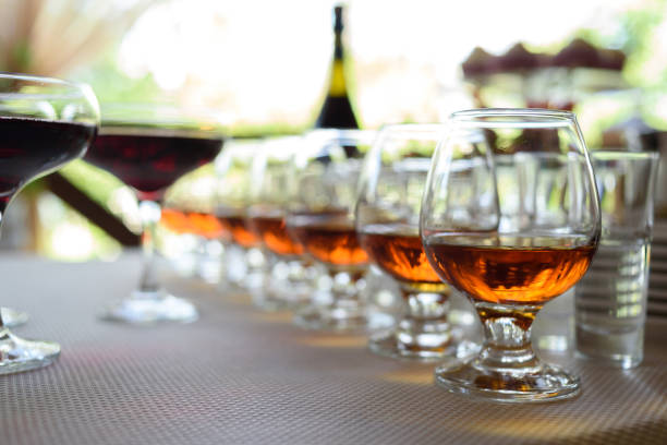 Row of glasses with whiskey or cognac on the table, free space. Strong alcohol in bar or restaurant. Transparent glasses with alcoholic drink stock photo
