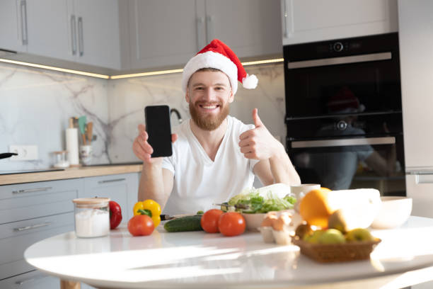 hombre mostrando teléfono móvil y pulgar hacia arriba en la mesa - salt domestic kitchen bowl sparse fotografías e imágenes de stock