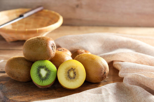 primo piano kiwi dorato maturo e kiwi verde su sfondo di legno. concetto di frutta sana. - kiwi foto e immagini stock