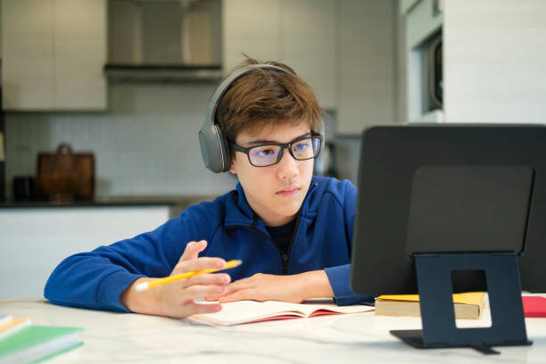 Student boy with tablet computer learning at home stock photo