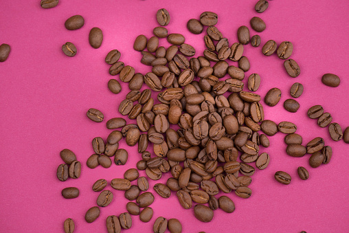 Roasted coffee beans on a textured background,empty copy space for text, pink background