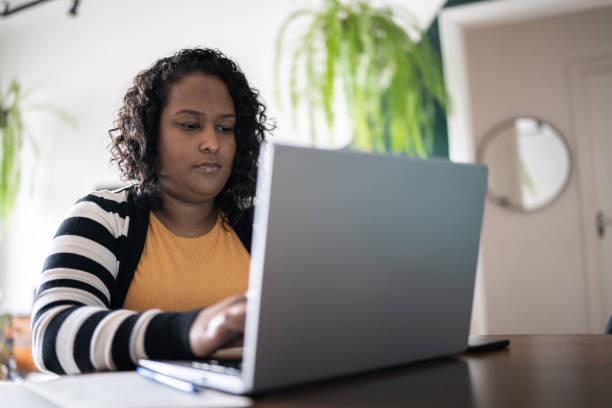 istock Mid adult woman using laptop at home 1346876968