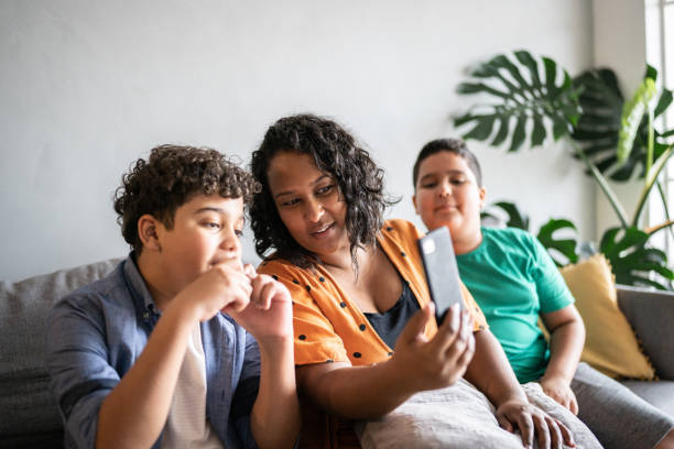 Mother and son on a video call using smartphone at home Mother and son on a video call using smartphone at home family dependency mother family with two children stock pictures, royalty-free photos & images