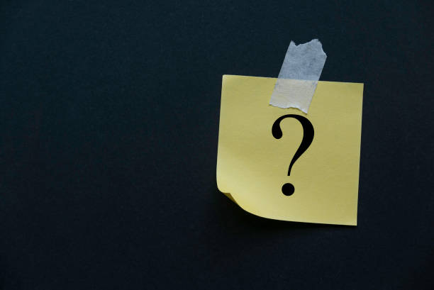 istock Yellow paper attached to the black wall written with question symbol. 1346881576