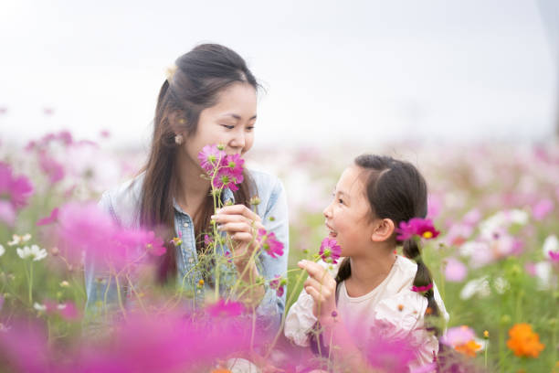 istock Mother and daughter playing in a flower field 1346883792
