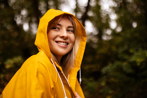 Young woman in yellow raincoat walking in rainy day