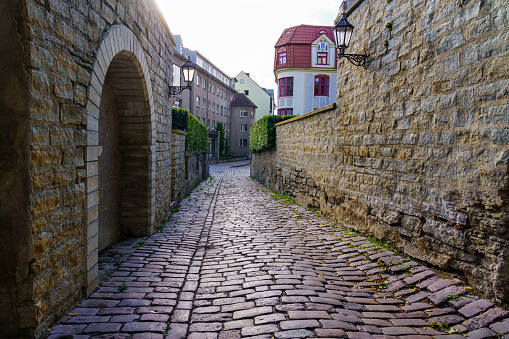 Medieval cobbled alley with arches and ancient stone wall. Tallinn Estonia.