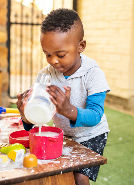 Smiling little boy making a mess while playing at a table outside stock photo