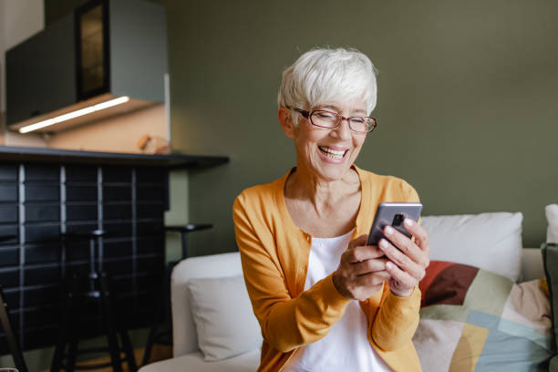 istock Senior woman uses a mobile phone at home 1346887126