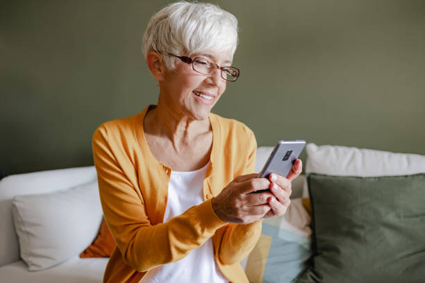 istock Senior woman uses a mobile phone at home 1346887227