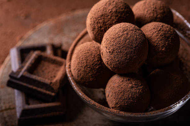 chocolate truffles Tasty dark chocolate truffles with cocoa dusting on a brown background tartuffo stock pictures, royalty-free photos & images