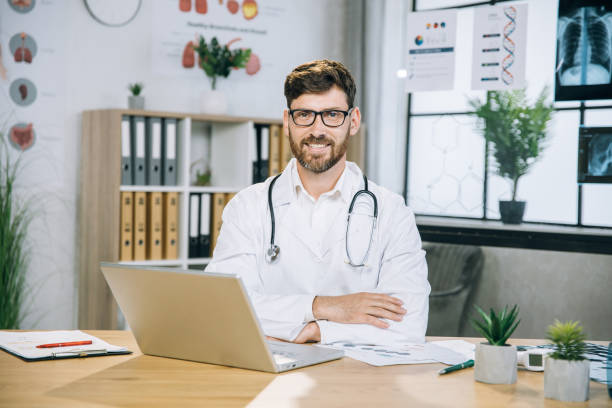 istock Caucasian doctor sitting at desk and smiling on camera 1346890464